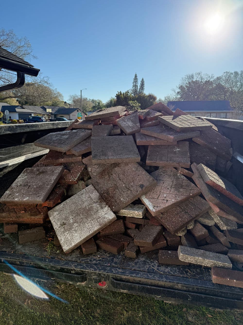 Piled bricks in a truck bed, ready for landscaping or construction projects. Sun shining overhead.