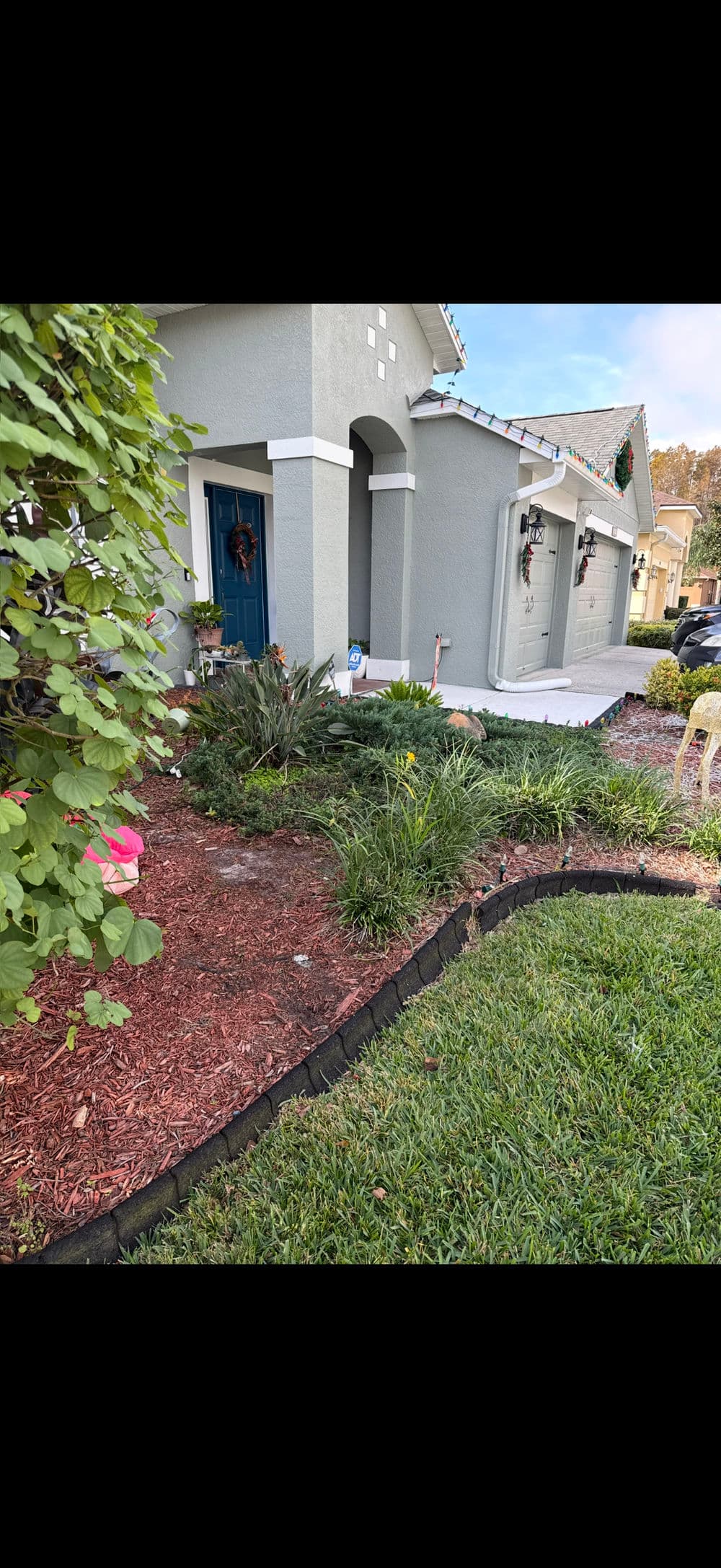 House exterior with landscaped garden and decorative elements, showcasing vibrant plants and mulch.