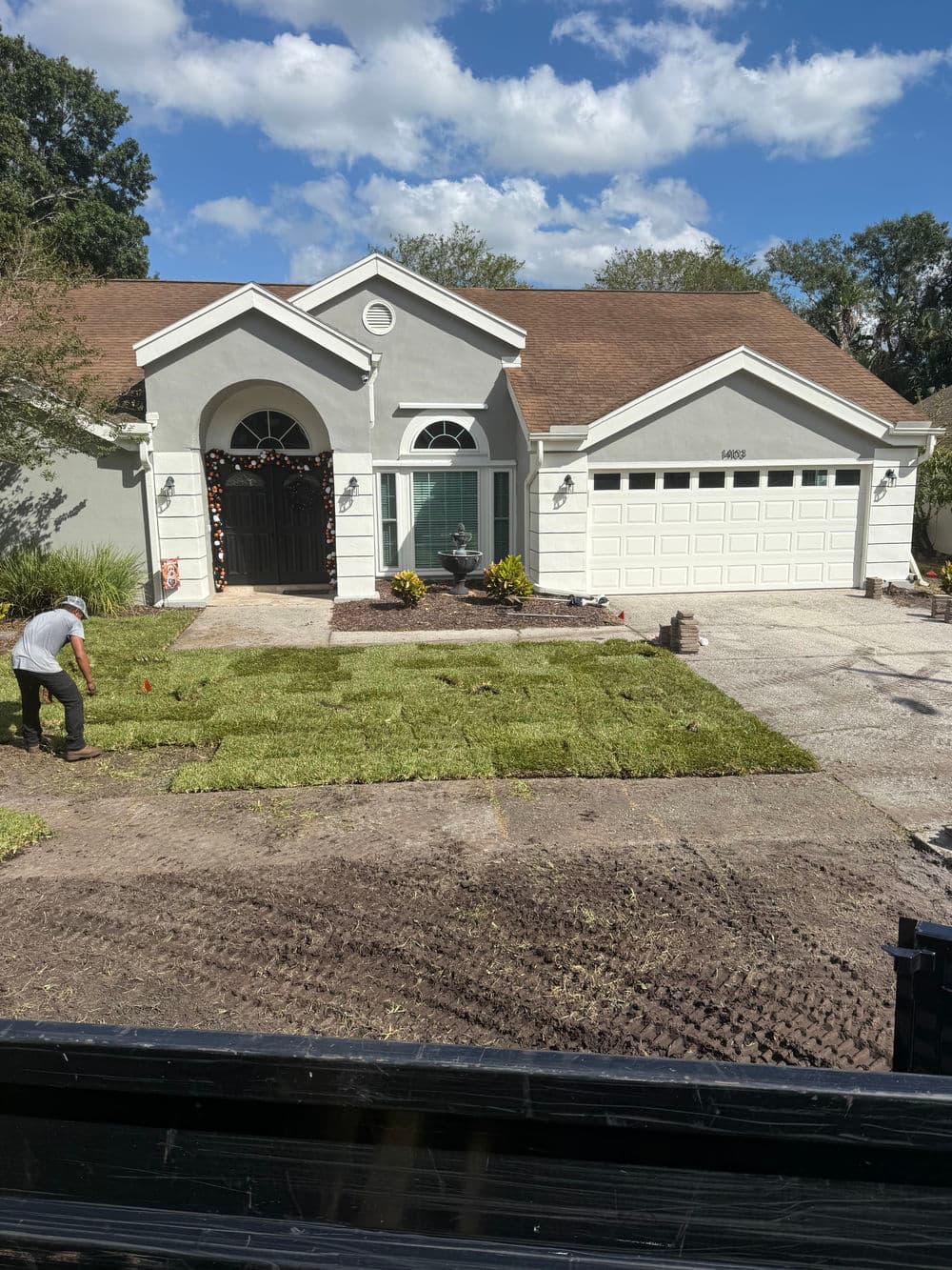 Lawn installation in front of a modern home with landscaped yard and cloudy sky.